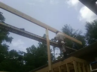 Carpenter setting a ridge beam over a new addition frame — Ice Dam Removal by Roofing Brothers in Whitleyville