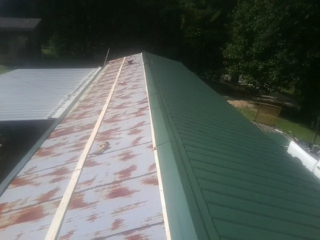 Old rusted panels beside newly installed green metal roofing — Wind Damage Roof Repair by Roofing Brothers in Whitleyville