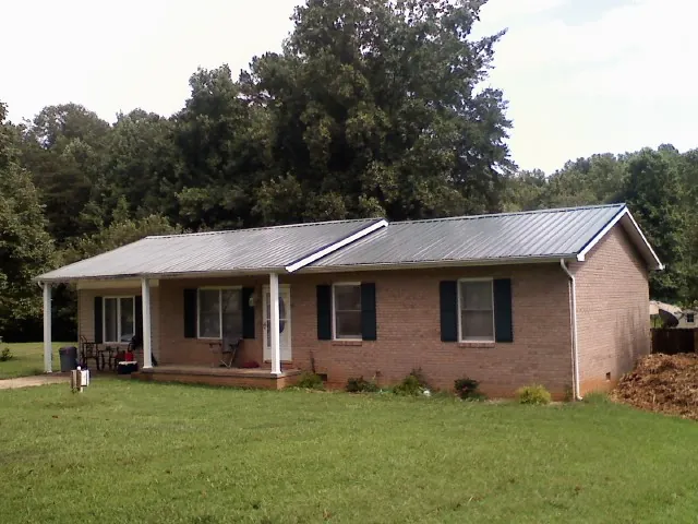 Gray metal roof on a brick ranch house with a side carport in Whitleyville