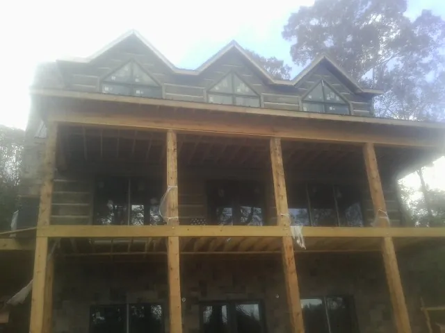 Dormers and porch framing on a large log home under construction — Roof Coating work by our crew in Whitleyville