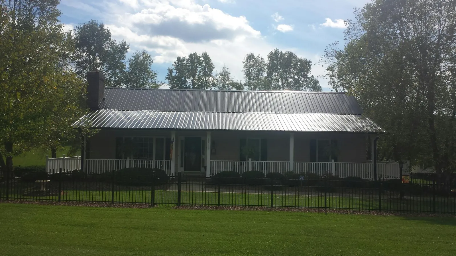 Gray metal roof on a brick ranch with a full width front porch — Gutter Guard Installation work by our crew in Whitleyville