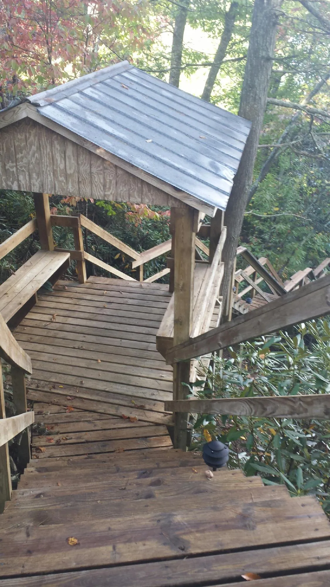 Metal roofed shelter over wooden steps on a wooded walkway — Skylight Repair & Installation work by our crew in Whitleyville