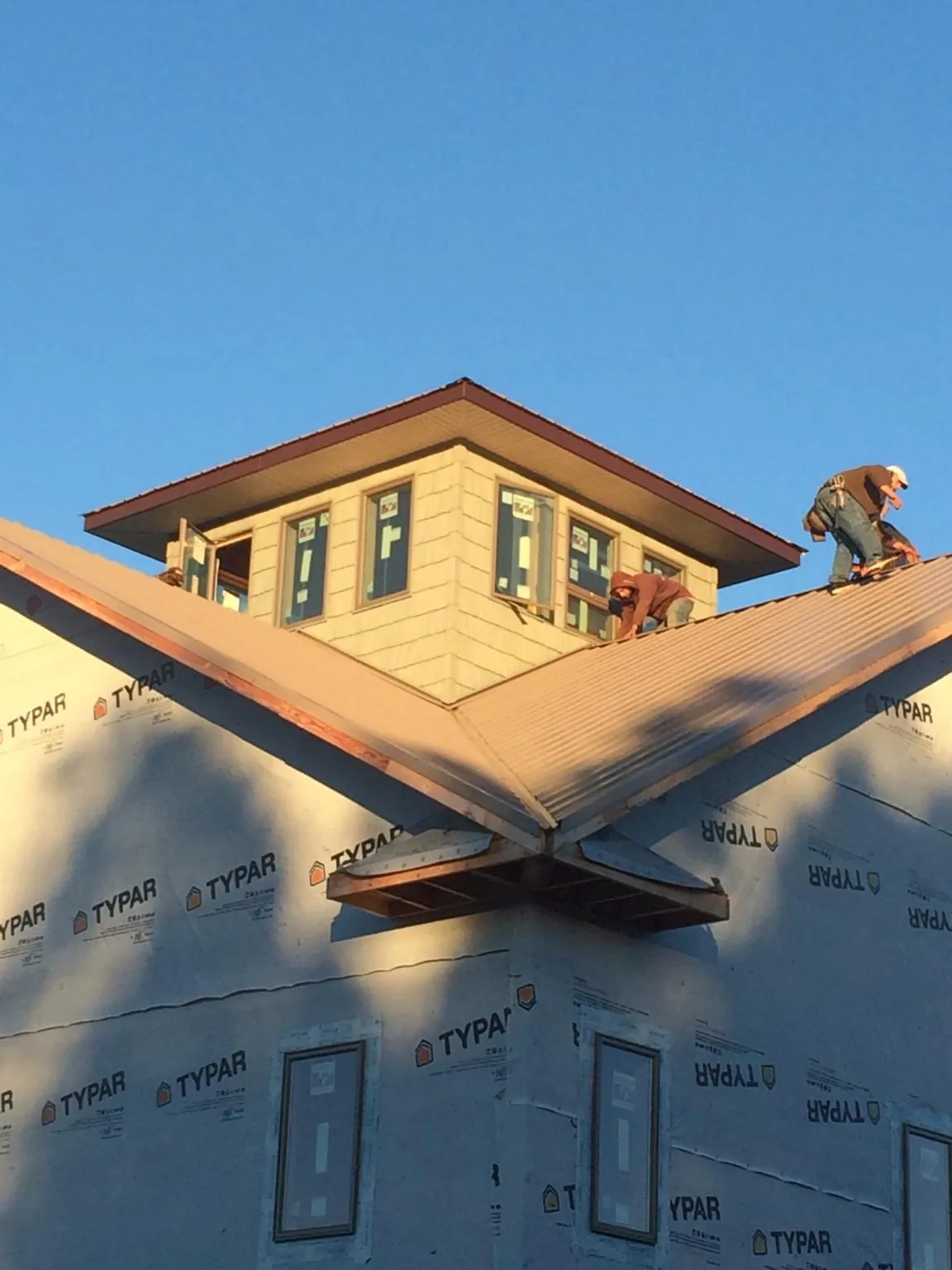 Roofers working around a rooftop cupola on a new metal roof at sunset — Roof Waterproofing in Whitleyville by Roofing Brothers